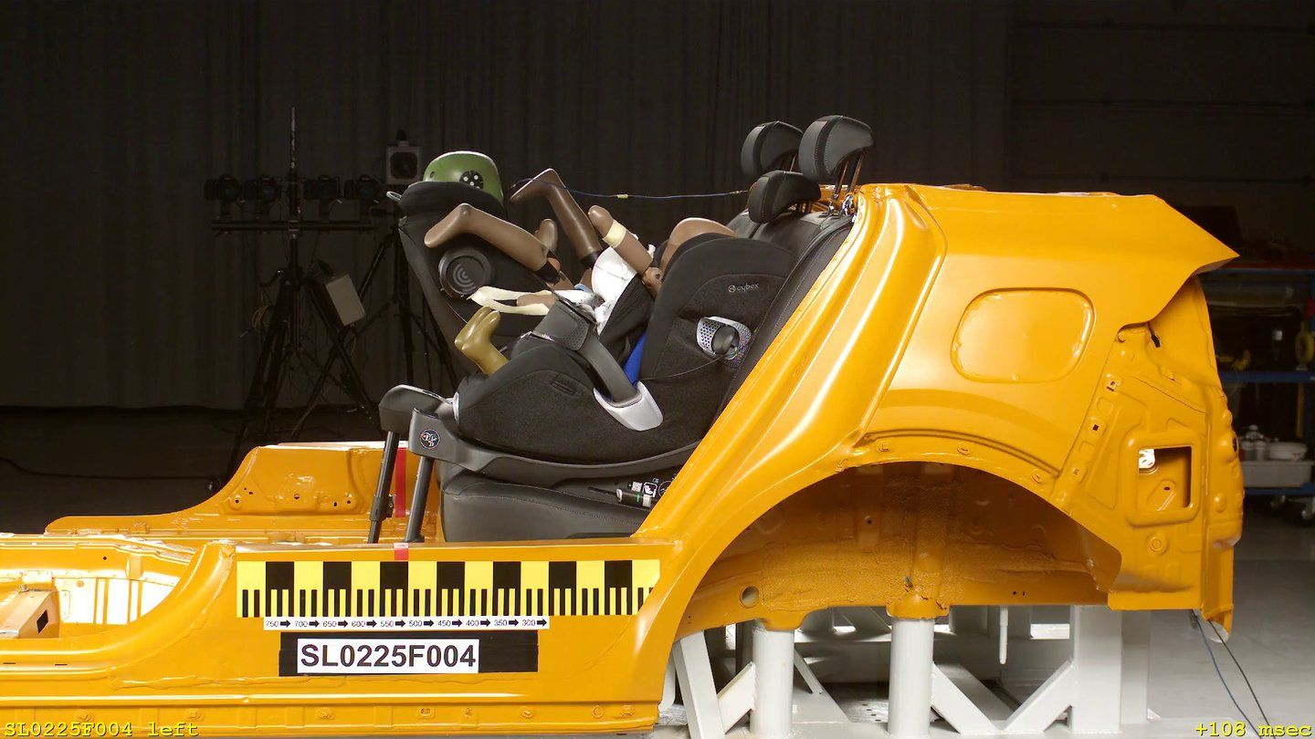 Image de caméra rapide d'un crash-test frontal, sur une caisse de voiture jaune, un mannequin enfant installé dans un siège Cybex Anoris T2 i-Size bascule vers l'avant, incrustations « SL0225F004 left » et « +108 msec »