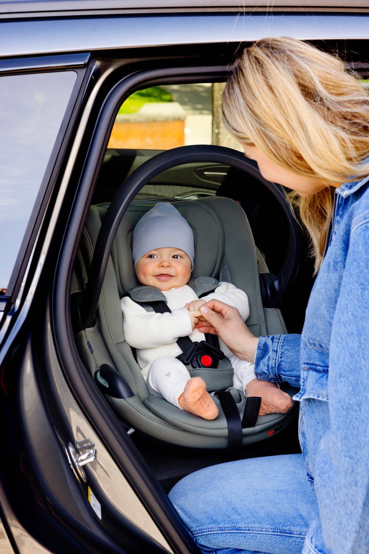 Une maman installe son bébé dans un BeSafe Go Beyond à l'arrière d'une voiture.