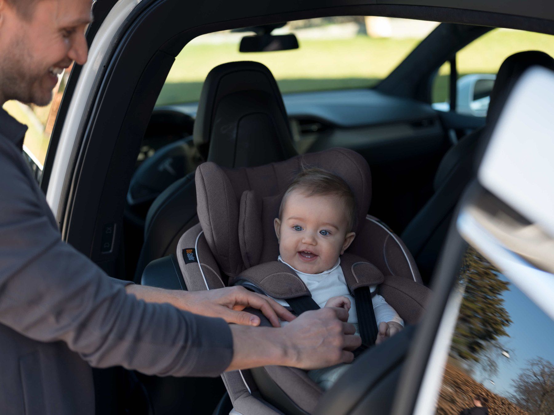 Un papa attache un bébé dans un BeSafe iZi Twist B à l'arrière d'une voiture.