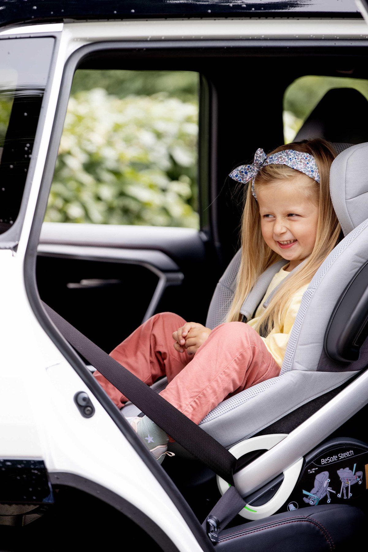 Une fillette souriante assise dans un BeSafe Stretch, porte ouverte.