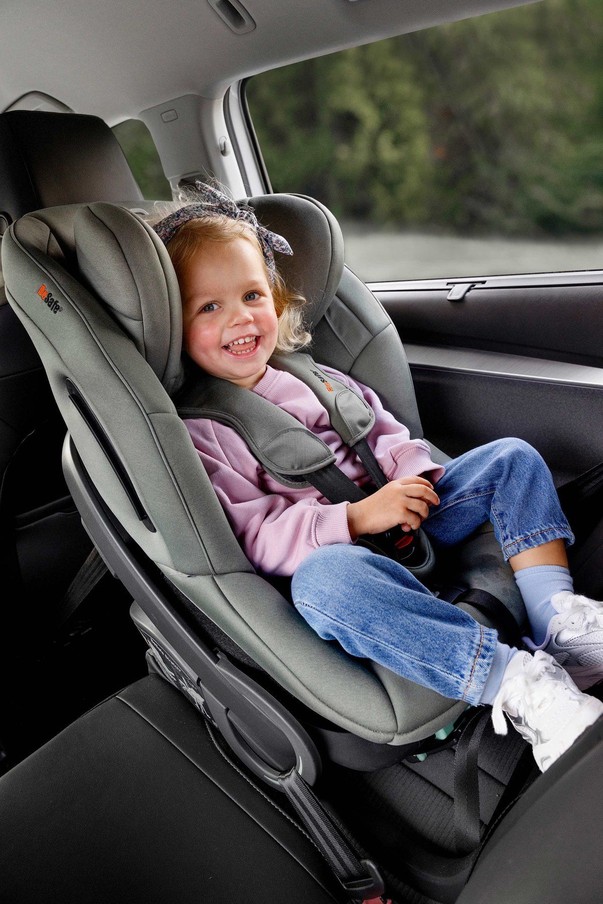 Une petite fille souriante dans un BeSafe Stretch B, dos à la route.