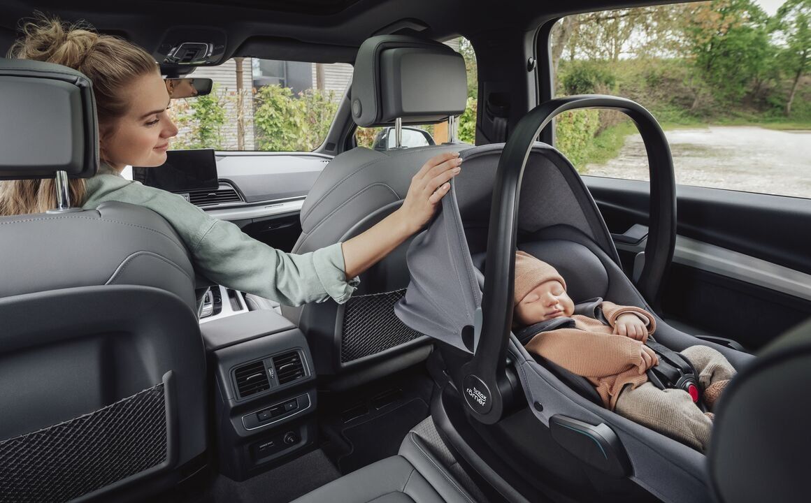 Une maman ajuste la couverture d'un bébé endormi dans la coque Baby-Safe Core, installée à l'arrière d'une voiture