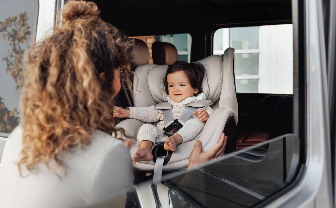 Une maman se penche vers sa petite fille attachée dans le Dualfix 5Z, à l'arrière d'une voiture
