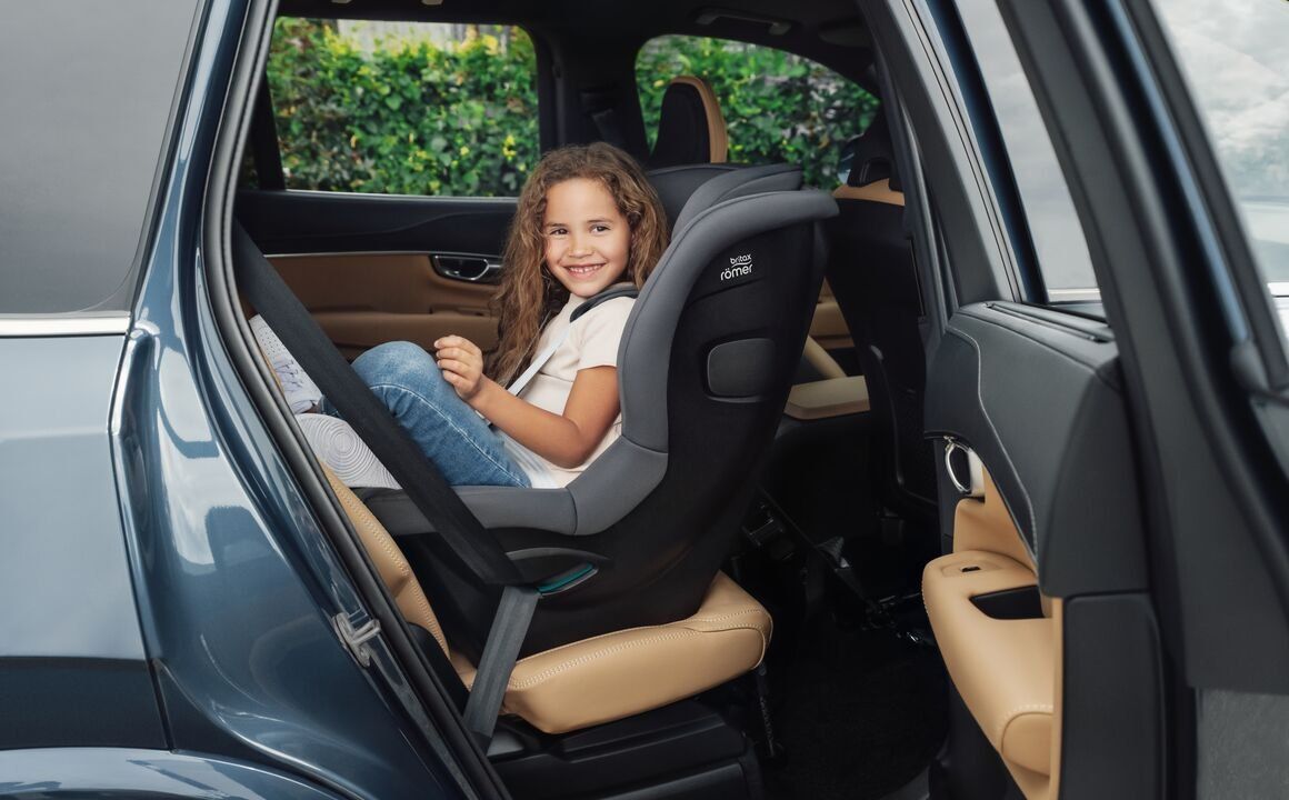 Une fillette souriante attachée dans le Safe-Way M installé dos à la route, à l'arrière d'une voiture