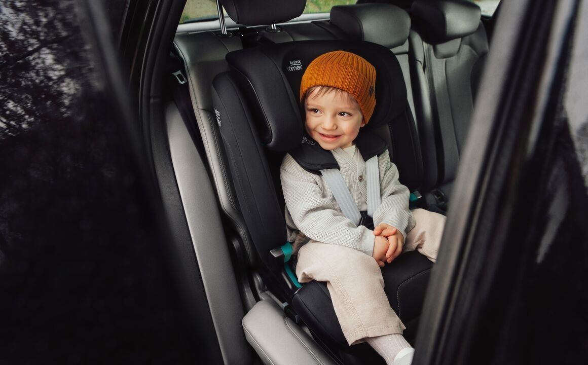 Un petit garçon en bonnet orange, attaché dans le Versafix à l'arrière d'une voiture