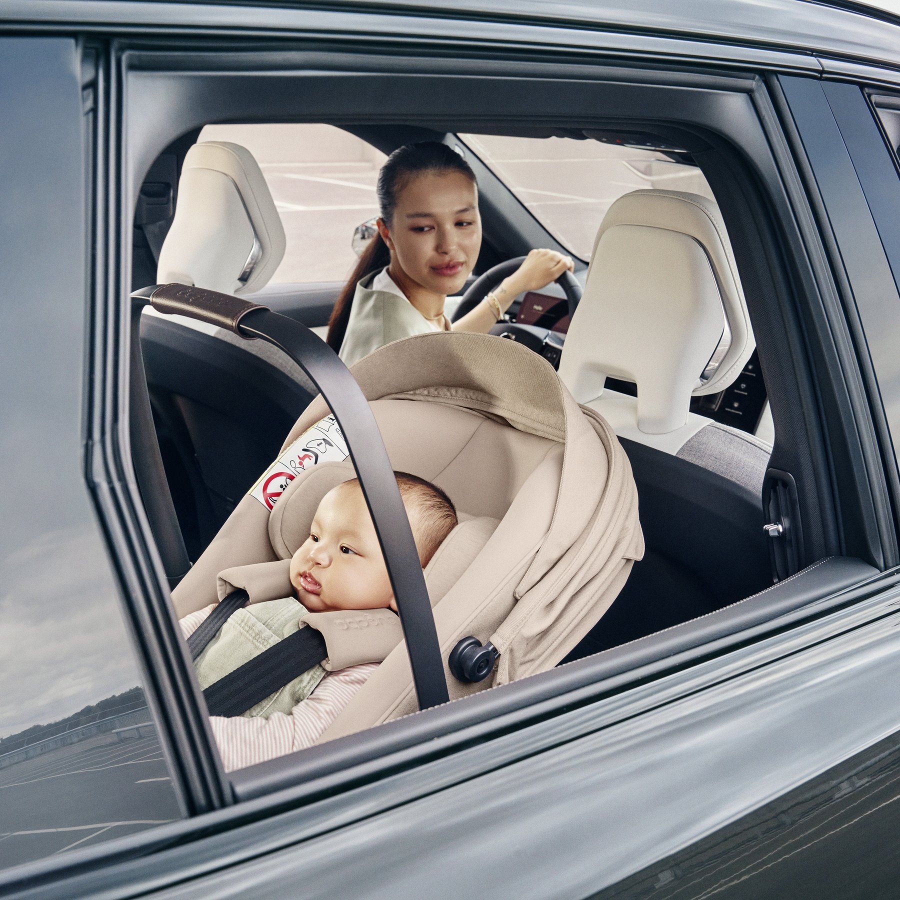 Un parent regarde un bébé installé dans le Bugaboo Otter by Nuna à l'arrière d'une voiture