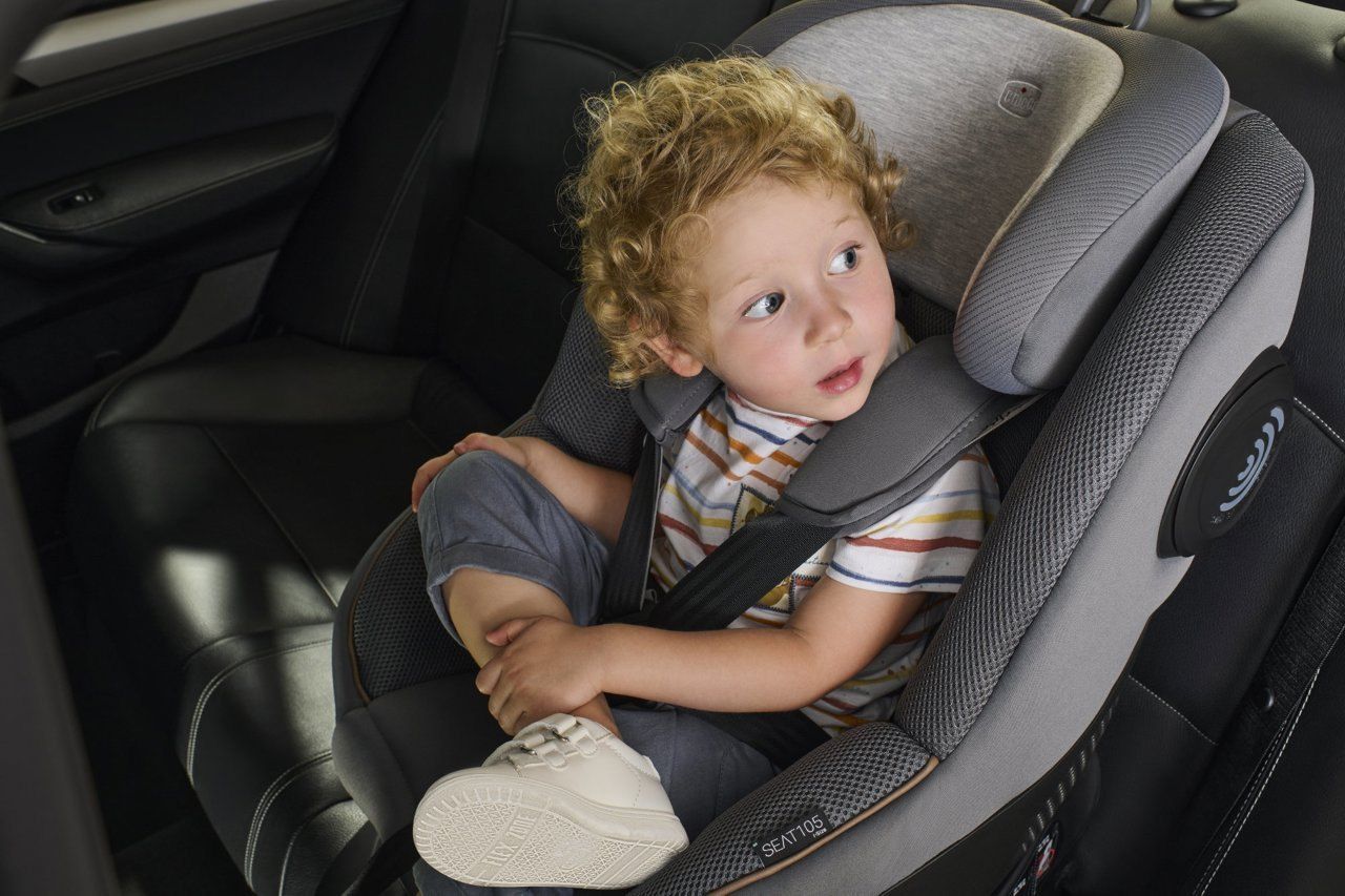 Un petit enfant assis dans le siège Chicco Seat105 face à la route, la ceinture de sécurité sur l'épaule.