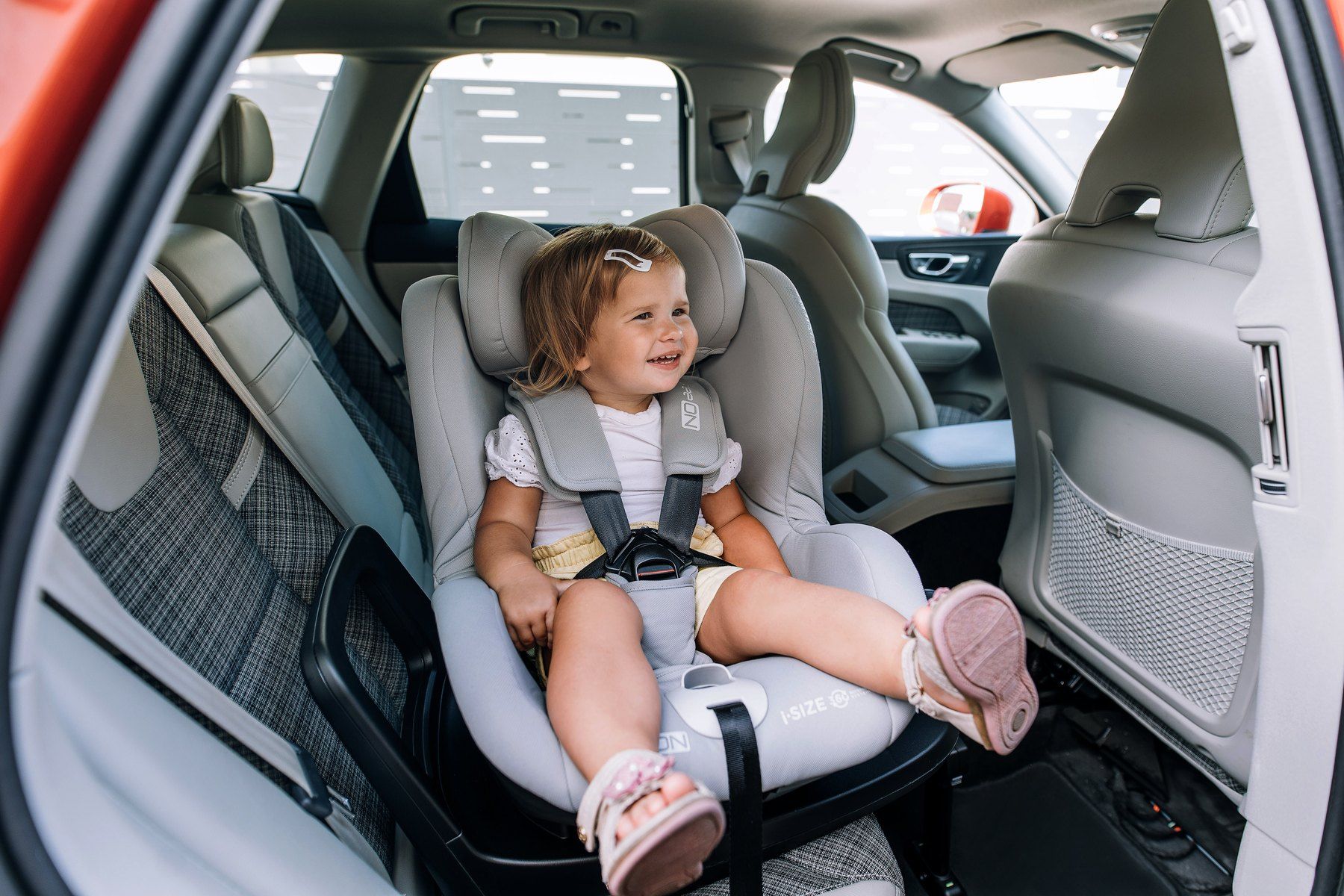 Une petite fille souriante, attachée dans un FreeOn Galaxy à l'arrière d'une voiture.