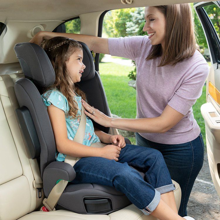Une maman ajuste la ceinture d'une fillette assise sur le rehausseur EverSure dans une voiture