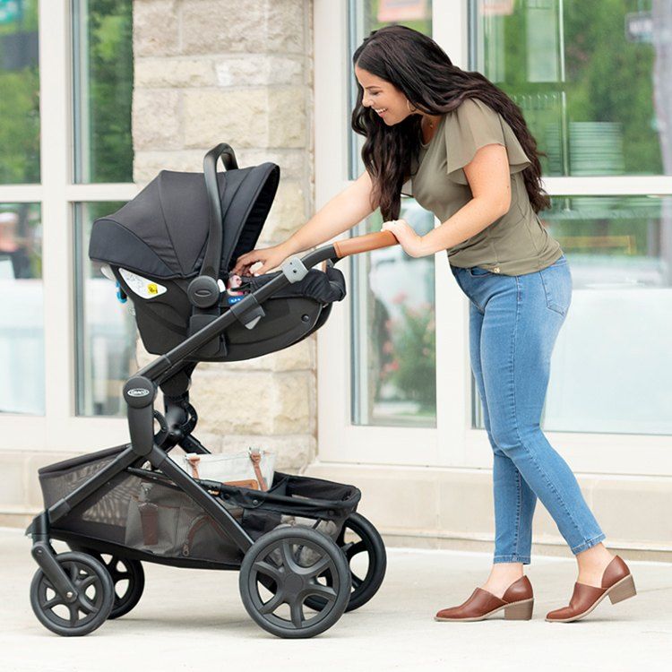 Une maman pousse une poussette sur laquelle est posée la coque SnugEssentials