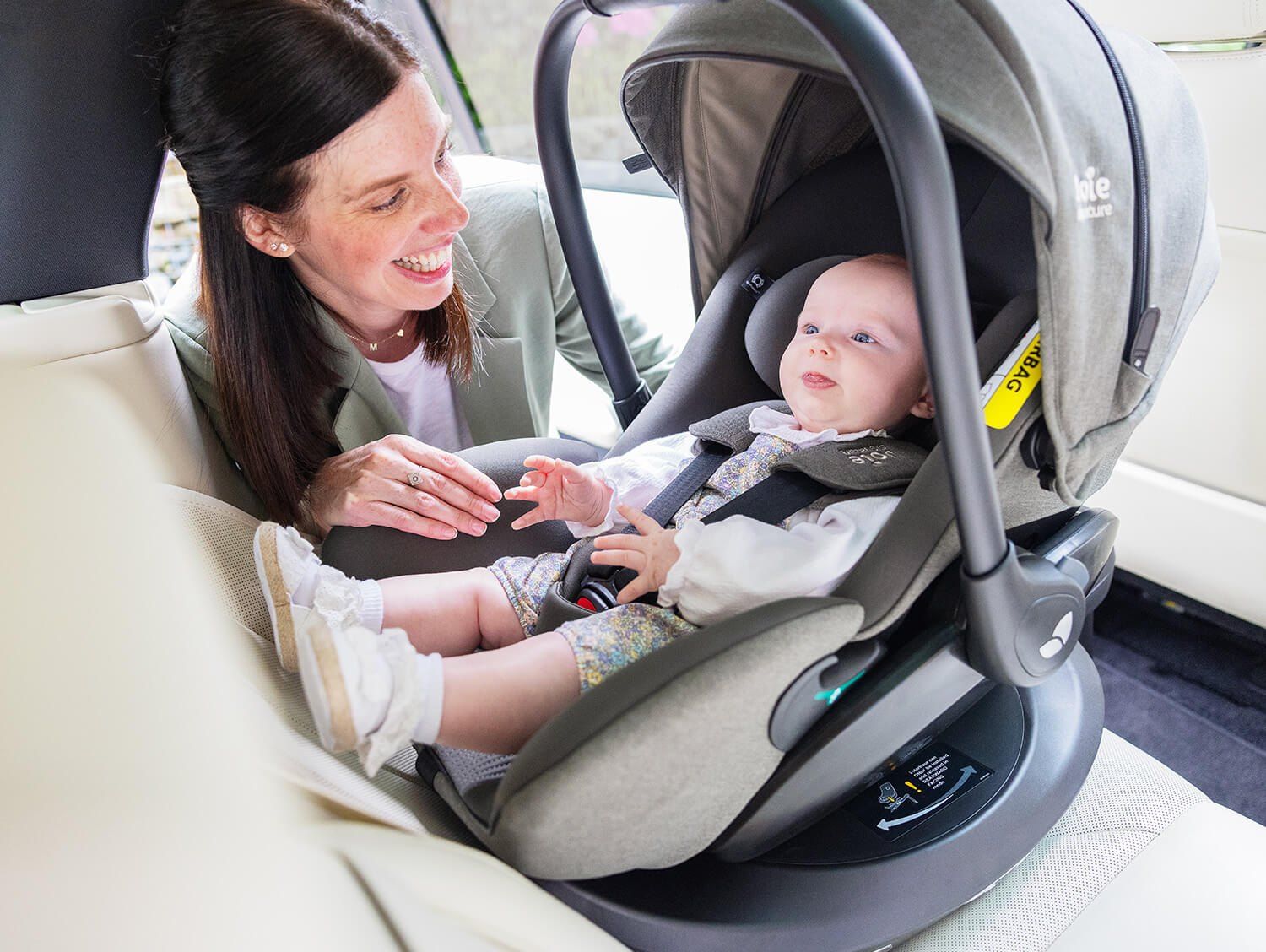 Une maman sourit à son bébé installé dans la coque Joie i-Level Pro sur la banquette arrière
