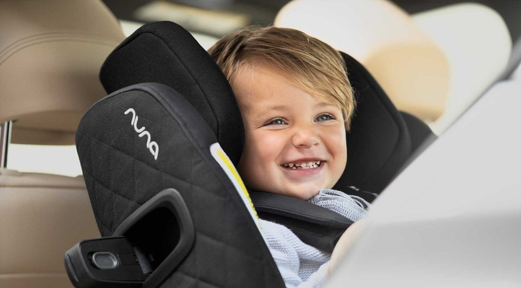 Un enfant qui sourit, installé dans le siège Norr à l'arrière d'une voiture.