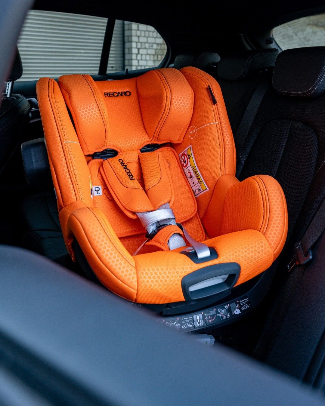 Un Recaro Toron 1 orange installé sur la banquette arrière d'une voiture