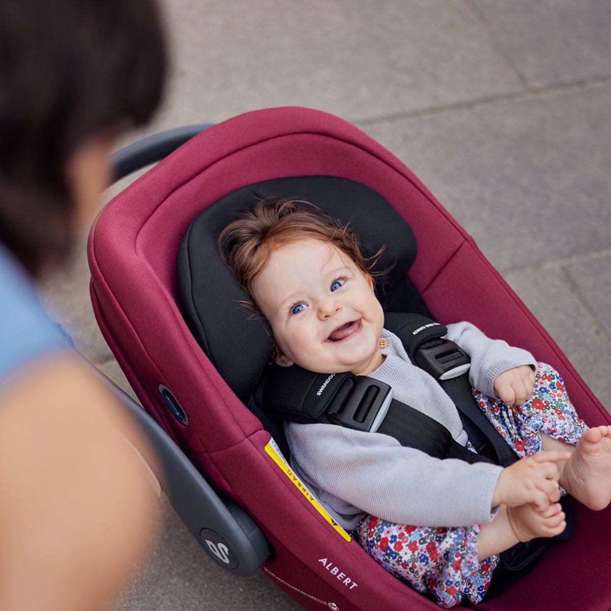 Un bébé qui sourit, installé dans la coque Swandoo Albert.